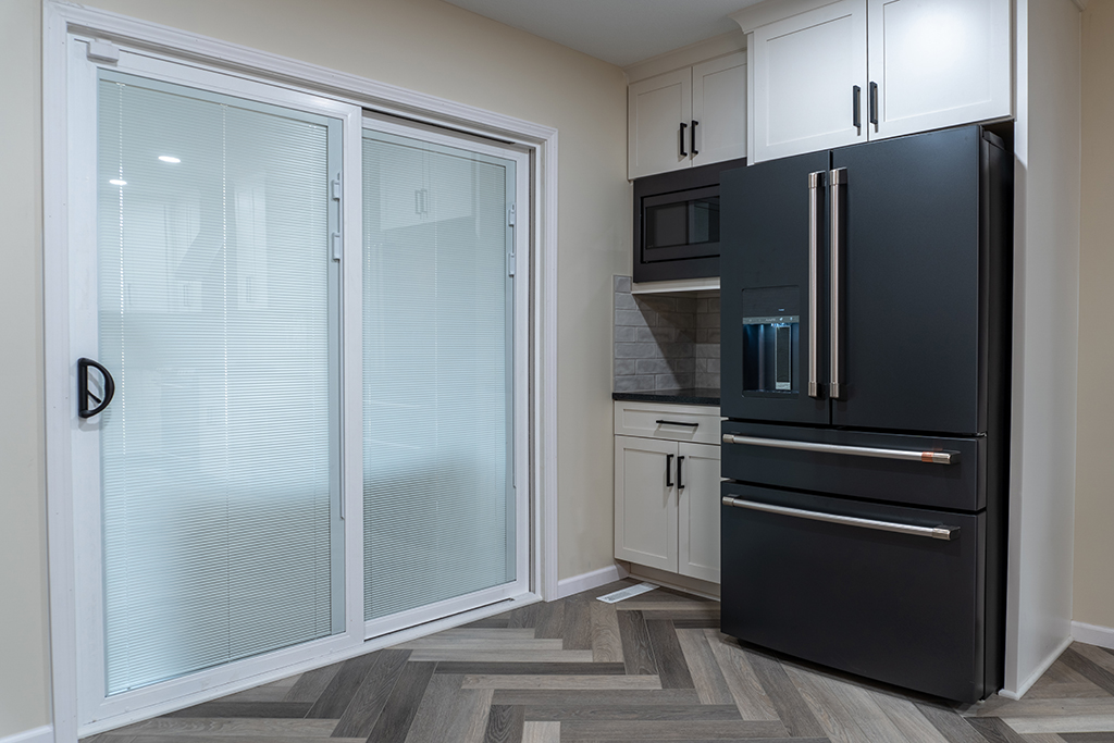 white kitchen with black fridge and sliding glass door
